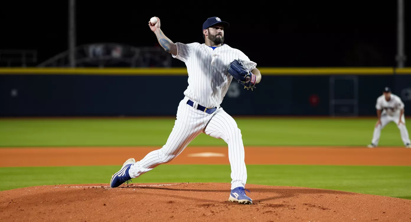 Baseball pitcher mid-delivery on the mound under stadium lights with the diamond visible behind